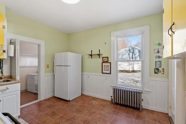 kitchen with sink, white cabinetry, radiator heating unit, white refrigerator, and tile patterned floors