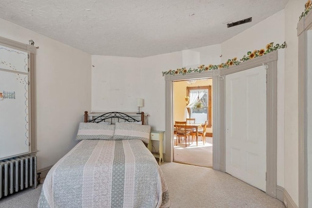 carpeted bedroom with radiator heating unit and a textured ceiling