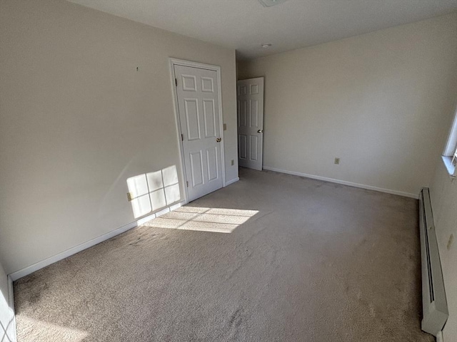 empty room featuring light colored carpet and a baseboard heating unit