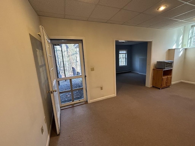 interior space featuring baseboard heating, a wealth of natural light, and a drop ceiling