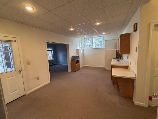 basement featuring carpet floors, white fridge, and plenty of natural light