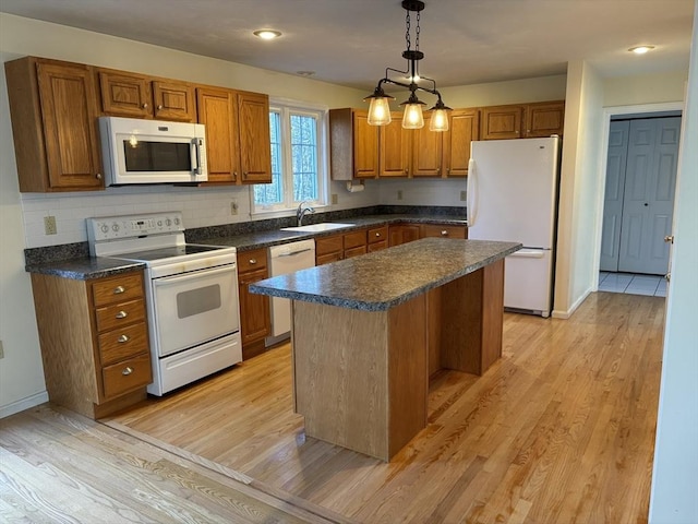 kitchen featuring pendant lighting, white appliances, light hardwood / wood-style flooring, and a kitchen island