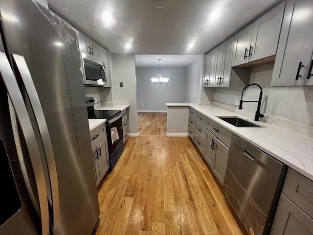 kitchen with sink, stainless steel appliances, a notable chandelier, light hardwood / wood-style floors, and gray cabinets