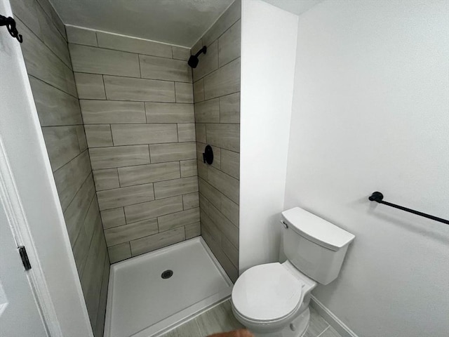 bathroom featuring tiled shower and toilet