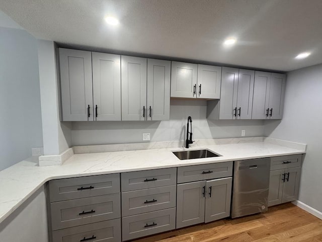 kitchen featuring sink, stainless steel dishwasher, gray cabinets, light stone countertops, and light wood-type flooring