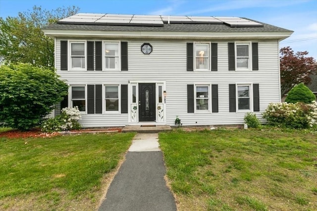 701 Nashua Rd, Dracut, MA 01826 - view of front facade with roof mounted solar panels, a front yard, and roof with shingles