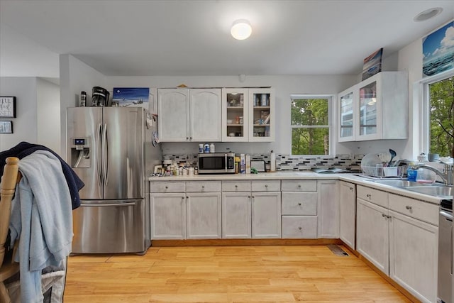 452 Nathan Ellis Hwy, Mashpee, MA 02649 - kitchen featuring appliances with stainless steel finishes, light countertops, light wood-type flooring, glass insert cabinets, and white cabinetry