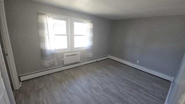 spare room featuring a baseboard heating unit, wood finished floors, and baseboards