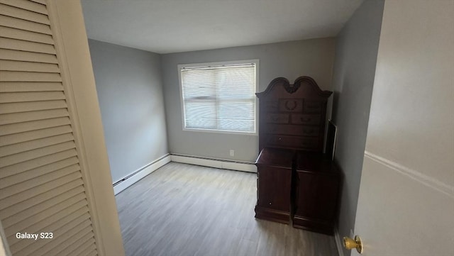 bedroom featuring a baseboard radiator, baseboards, and wood finished floors