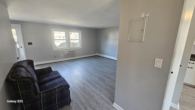 unfurnished living room featuring electric panel, baseboards, baseboard heating, and wood finished floors