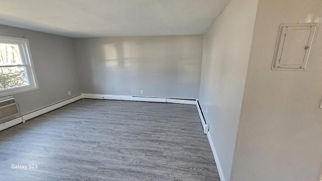 spare room with electric panel, baseboards, and wood finished floors