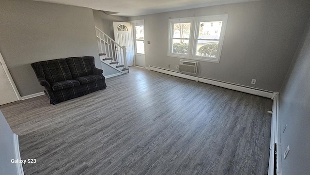 unfurnished room featuring stairway, a wall mounted AC, baseboards, and wood finished floors