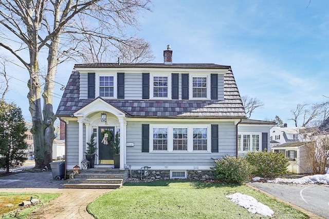 dutch colonial featuring a front lawn, a chimney, and a gambrel roof