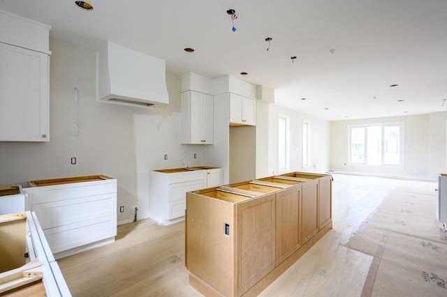 kitchen featuring light hardwood / wood-style floors, a kitchen island, and white cabinetry