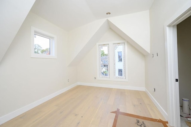 bonus room with plenty of natural light, vaulted ceiling, and light hardwood / wood-style flooring