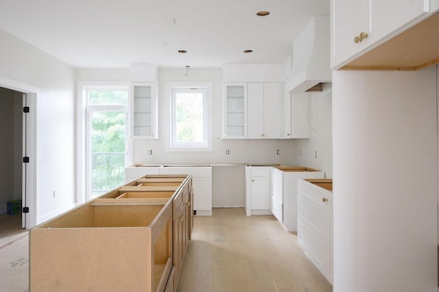 kitchen featuring white cabinets, a center island, and premium range hood