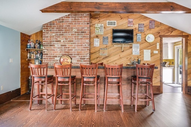 indoor dry bar featuring wood finished floors, wood walls, and baseboards
