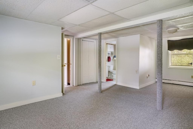 below grade area with carpet flooring, a baseboard heating unit, baseboards, and a drop ceiling