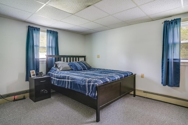 bedroom with multiple windows, carpet floors, a baseboard radiator, and a drop ceiling