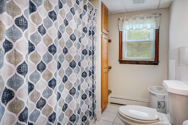 full bathroom featuring a baseboard heating unit, toilet, tile patterned floors, a paneled ceiling, and a shower with shower curtain