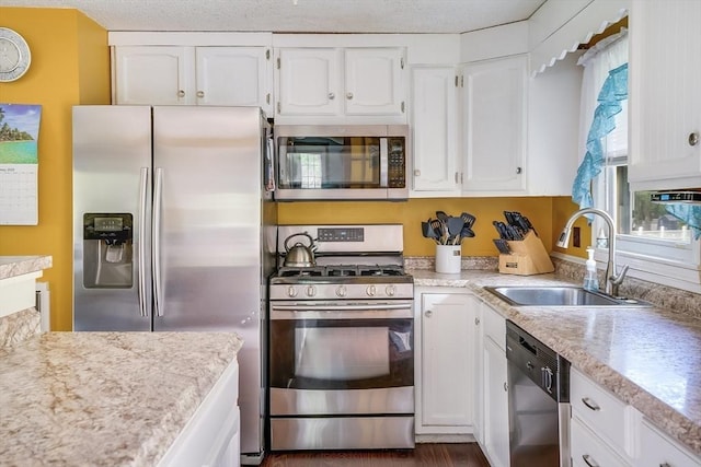kitchen featuring appliances with stainless steel finishes, a sink, white cabinetry, and light countertops