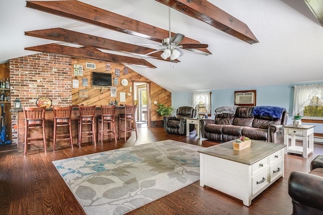 living room with ceiling fan, wooden walls, a dry bar, and dark wood-style flooring