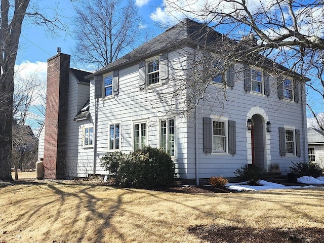 colonial house with a chimney and a front lawn