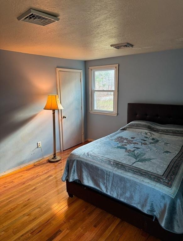 bedroom with hardwood / wood-style floors and a textured ceiling