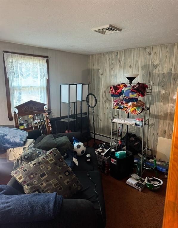 bedroom with a textured ceiling, carpet flooring, and wooden walls