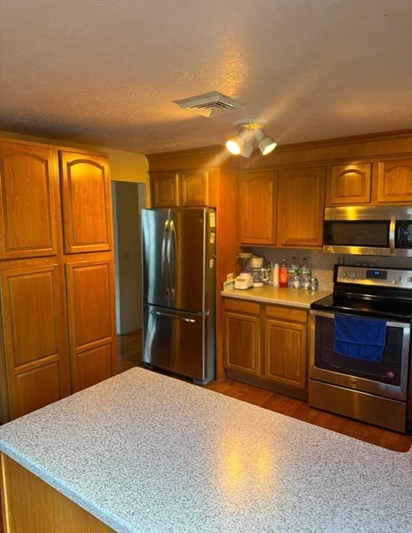 kitchen featuring light stone counters, dark wood-type flooring, a textured ceiling, and appliances with stainless steel finishes