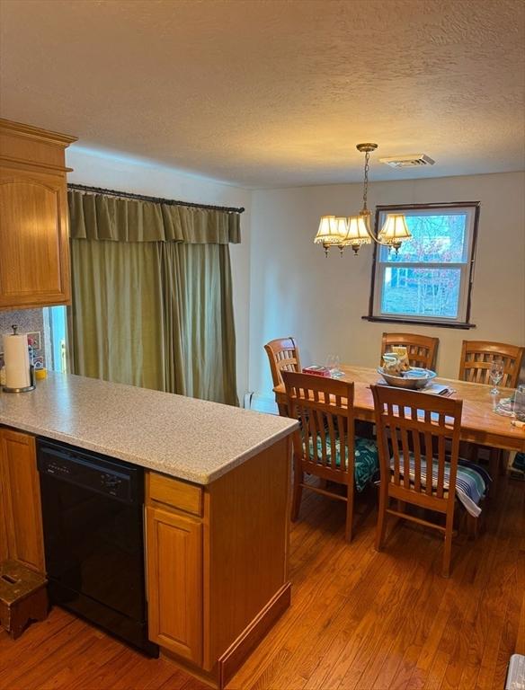 kitchen with a notable chandelier, hardwood / wood-style floors, a textured ceiling, dishwasher, and pendant lighting