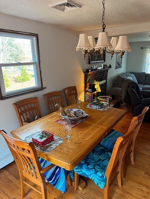 dining area with wood-type flooring, a textured ceiling, and a fireplace