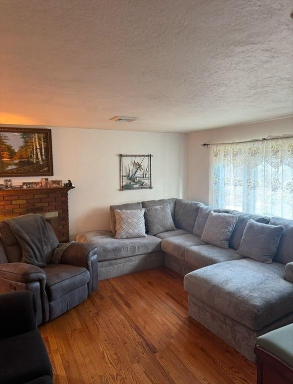 living room featuring hardwood / wood-style floors, a textured ceiling, and a fireplace