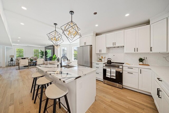 1135-1137 Hyde Park Ave Unit 1, Boston, MA 02136 - kitchen featuring stainless steel appliances, a sink, a chandelier, light wood-style flooring, and a kitchen breakfast bar