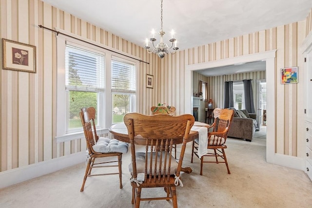 dining room featuring wallpapered walls, a chandelier, and light carpet