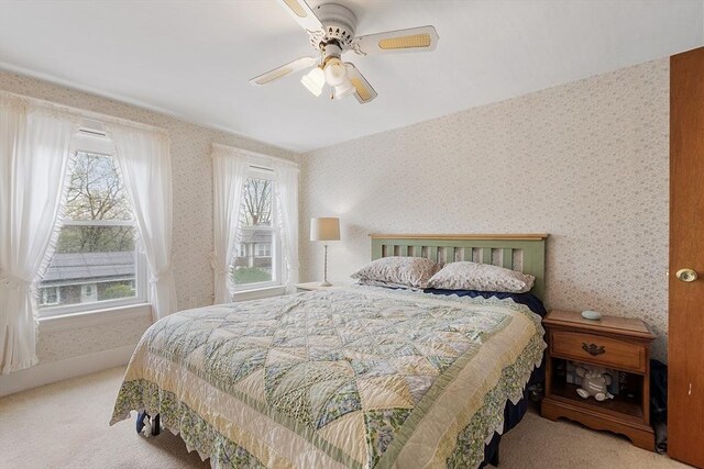 bedroom with wallpapered walls, carpet floors, multiple windows, and a ceiling fan
