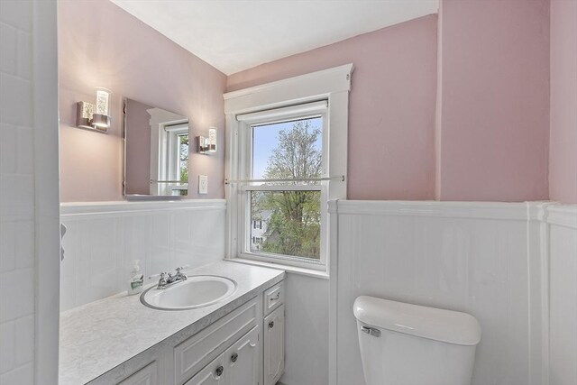 half bathroom featuring wainscoting, vanity, and toilet