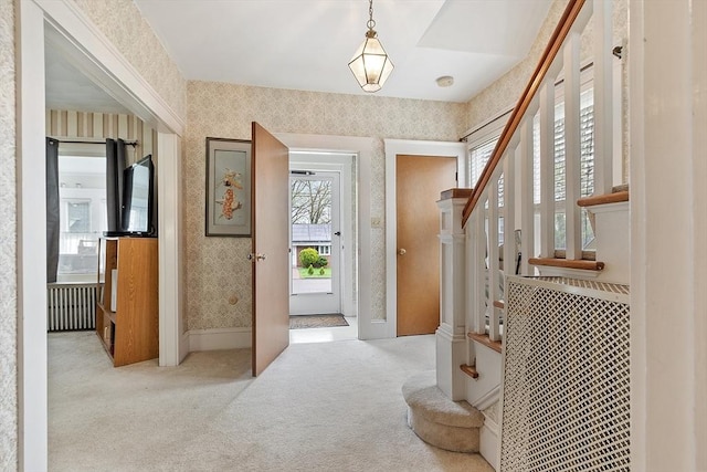carpeted foyer entrance with wallpapered walls and stairs