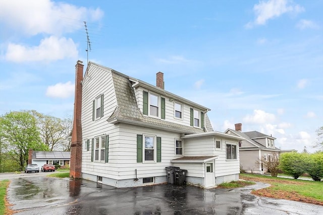 view of front facade featuring a chimney and a gambrel roof