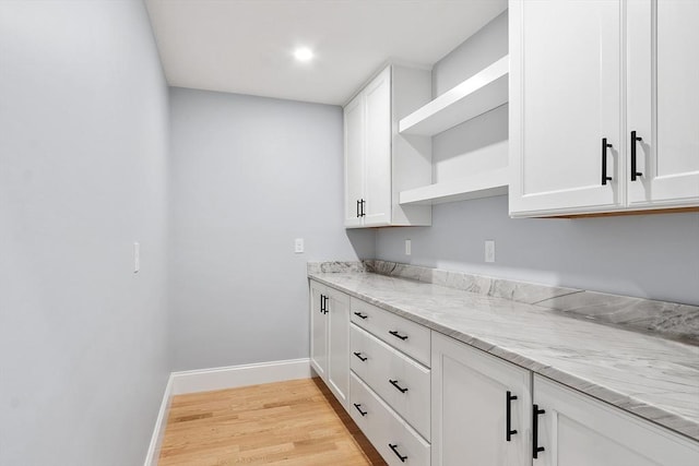 192 Tahattawan, Littleton, MA 01460 - kitchen with open shelves, light wood-style flooring, white cabinets, baseboards, and light stone counters