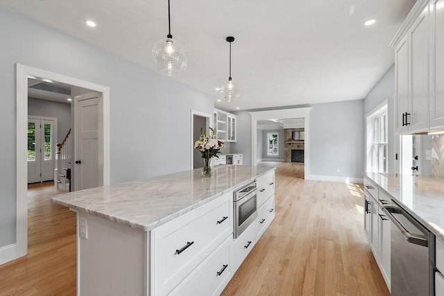 192 Tahattawan, Littleton, MA 01460 - kitchen with dishwasher, light wood-style flooring, white cabinetry, light stone counters, and a center island