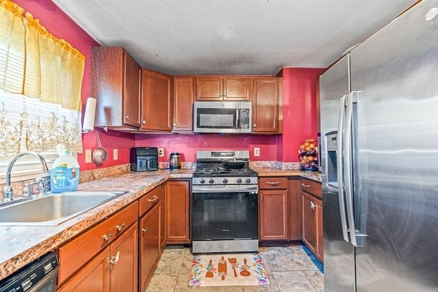 kitchen with brown cabinetry, stainless steel appliances, light countertops, and a sink