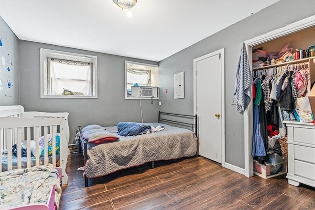 bedroom with electric panel, cooling unit, wood finished floors, and a closet