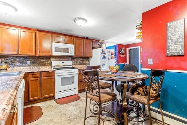 kitchen with backsplash, light countertops, brown cabinets, white appliances, and a sink