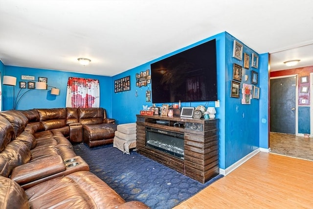 living area with a glass covered fireplace, wood finished floors, and baseboards