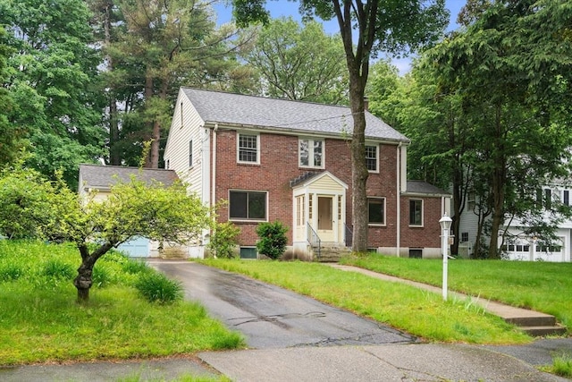 65 Kirkstall Rd, Newton, MA 02460 - colonial house featuring brick siding, driveway, entry steps, and a front lawn