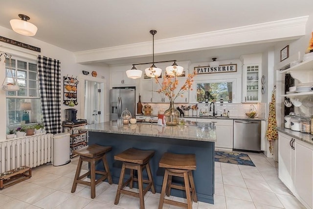 kitchen with decorative backsplash, radiator heating unit, a breakfast bar, stainless steel appliances, and white cabinetry