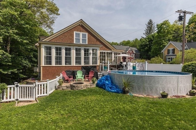 44 Fairview St, Fitchburg, MA 01420 - rear view of house with a fire pit, a sunroom, a lawn, fence, and an outdoor pool