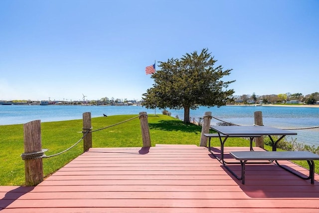 wooden deck featuring a water view and a lawn