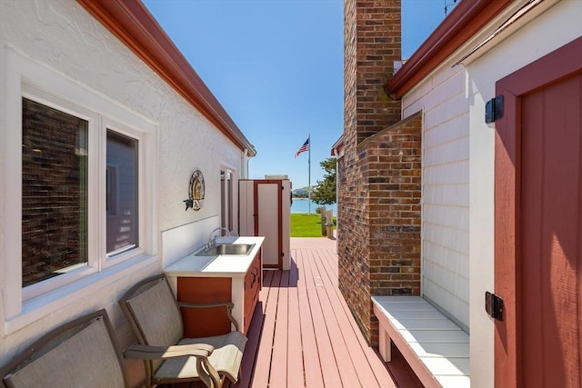 wooden deck with a water view and a sink